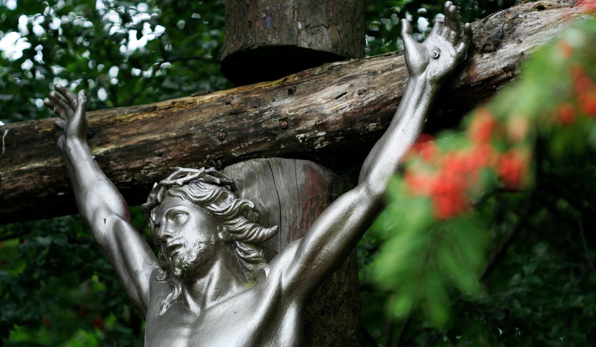 statue of jesus on the cross in front of a holly tree