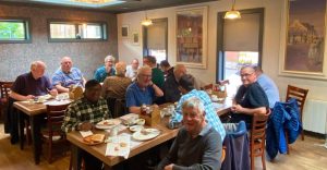 Group of men sitting around a table eating breakfast